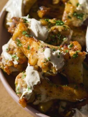 Greek chicken wings on a platter with feta sauce.