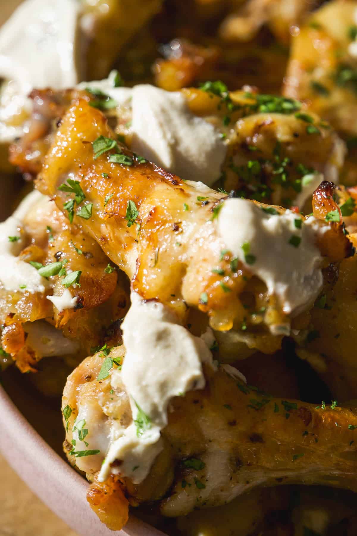Greek chicken wings on a platter with feta sauce and parsley.