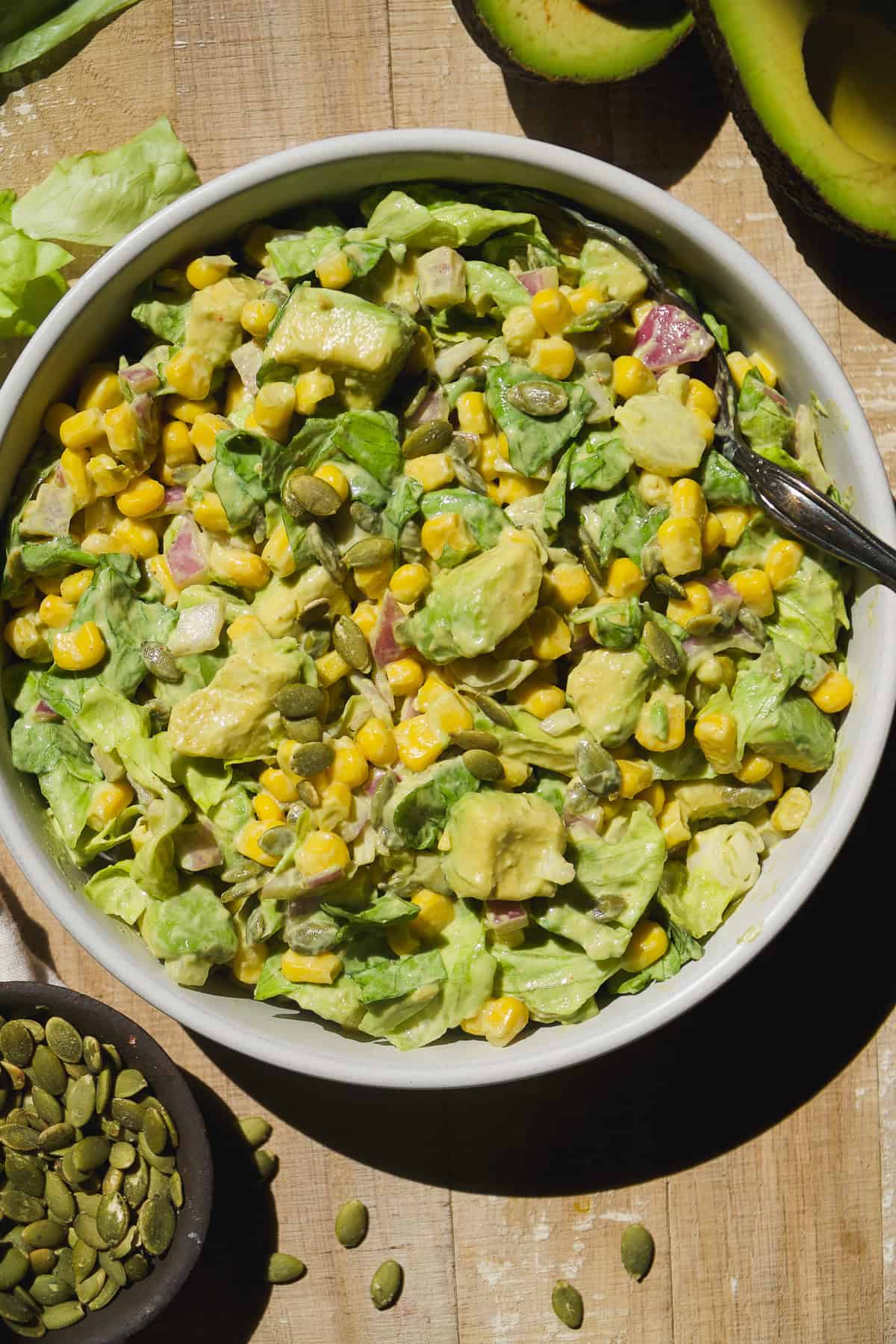 Overhead view of avocado and corn salad tossed with yogurt mustard dressing.