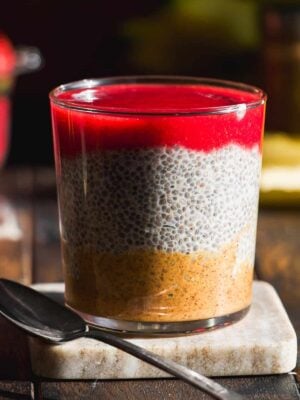 Almond butter and jelly chia seed pudding in a glass jar with a spoon.