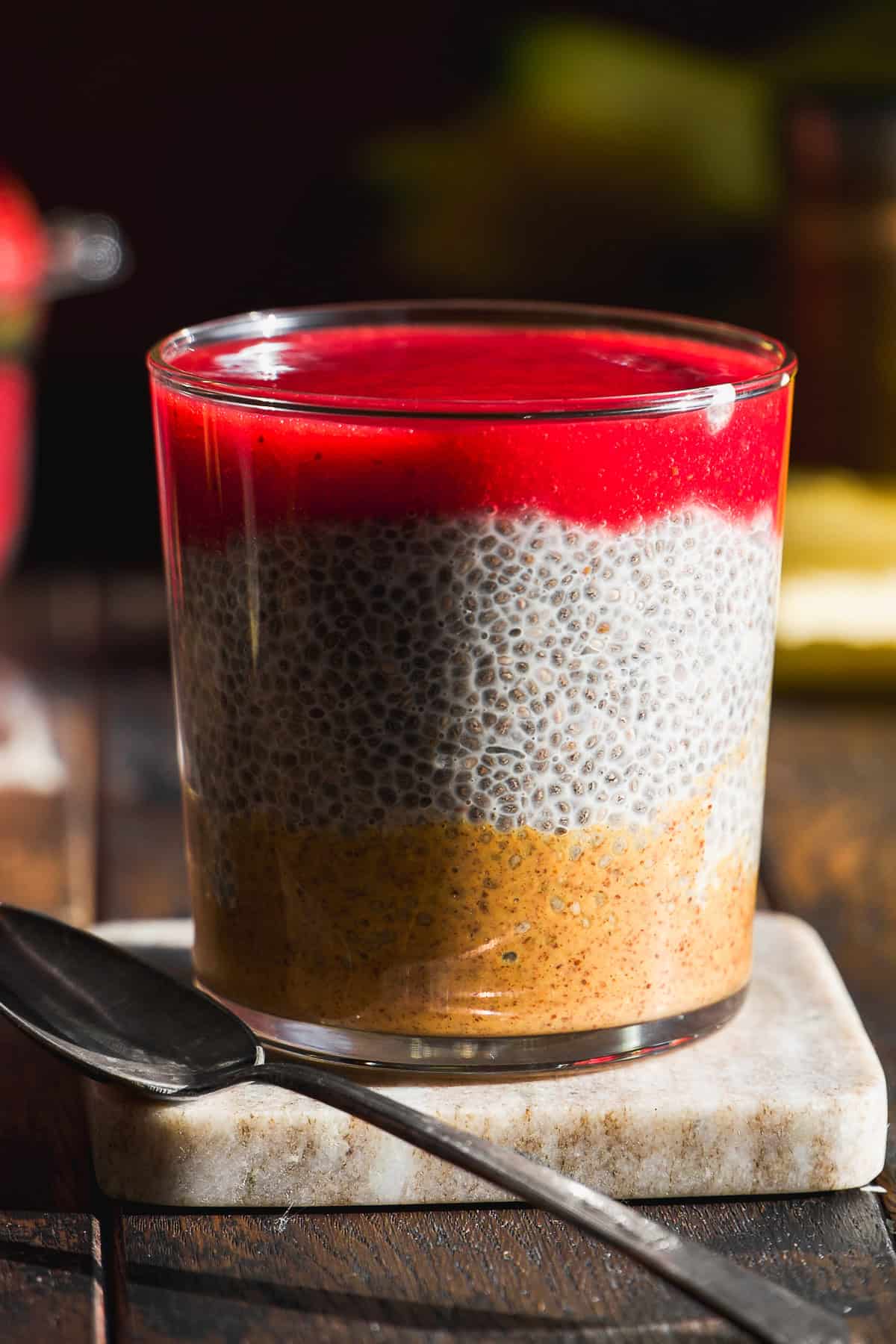Almond butter and jelly chia seed pudding in a glass jar with a spoon.