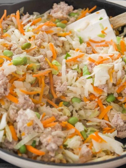 Egg roll in a bowl ingredients cooking in a skillet.