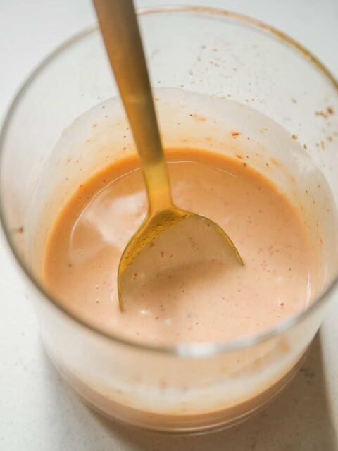 Bang bang sauce mixed in a glass jar with a gold spoon.