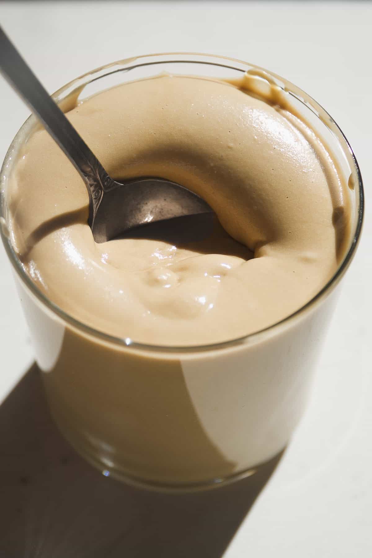 Maple cream in a glass jar with a spoon dipping inside.