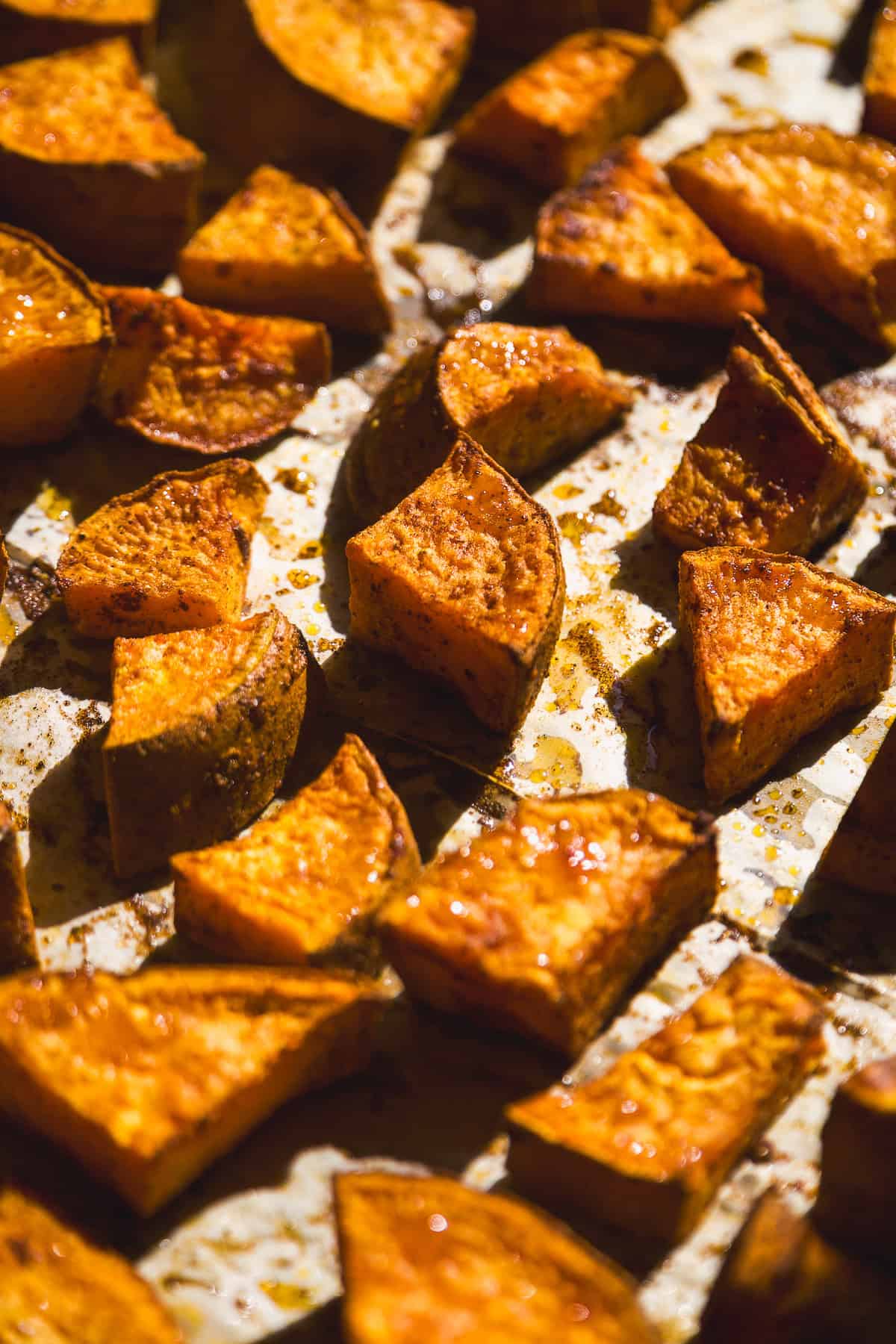 Roasted sweet potatoes on parchment paper with seasonings.
