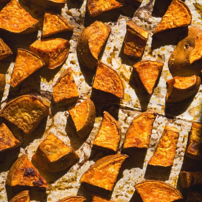 Baking sheet with roasted sweet potatoes coated in seasonings.