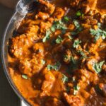 Chicken butter in a skillet with a tomato curry sauce.