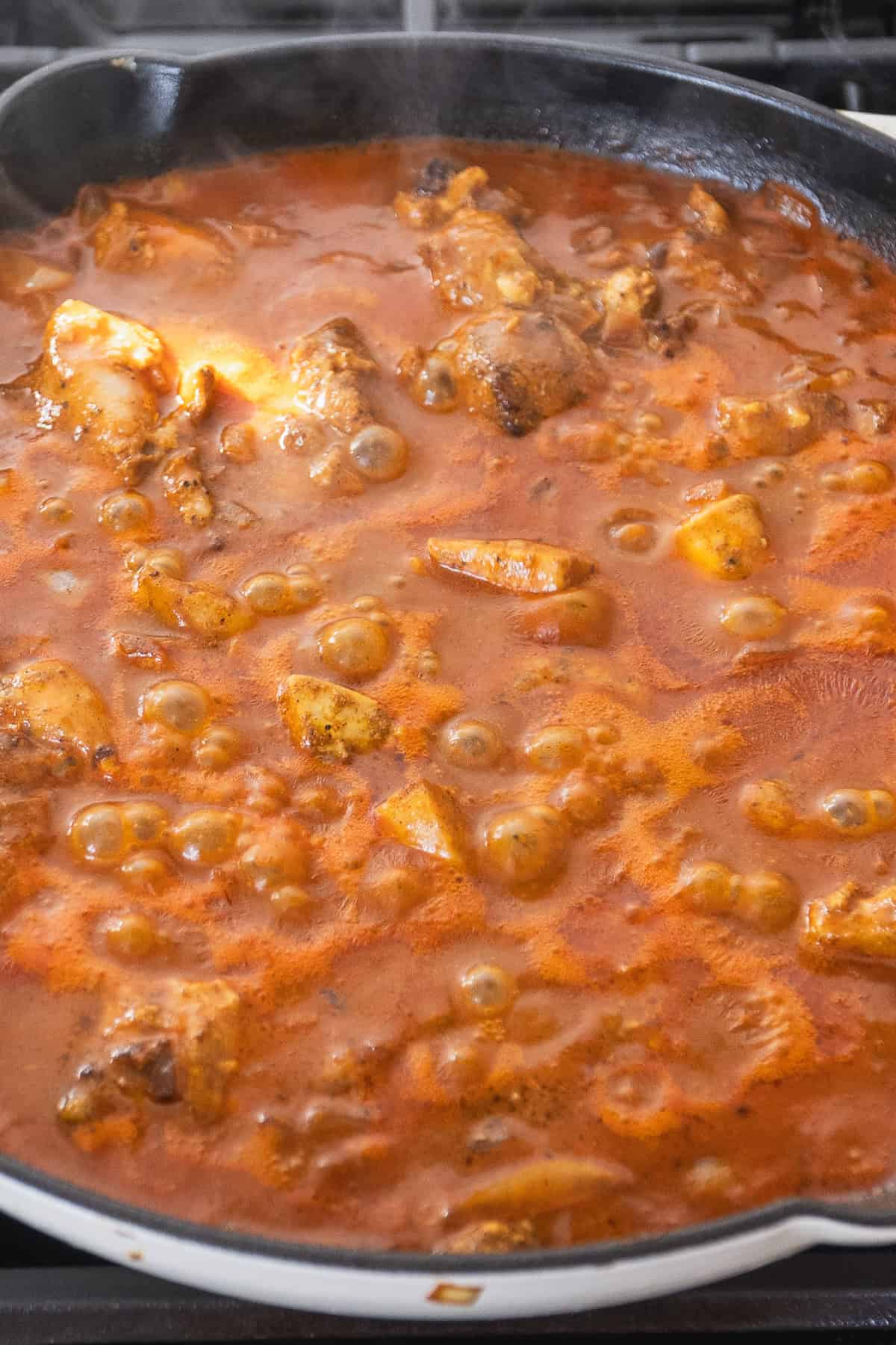 Chicken cooking in a tomato curry sauce.