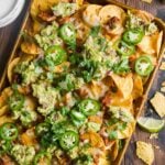 Chicken nachos in a baking pan with toppings.