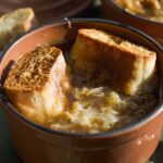 French onion soup in a miniature pot with two slices of bread on top.