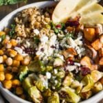 Harvest salad in a bowl with kale, roasted vegetables, chickpeas, and feta cheese.