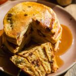 Stack of healthy pumpkin pancakes on a plate with a fork taking a bite.