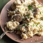 Mushroom risotto with parmesan on a plate with a fork.