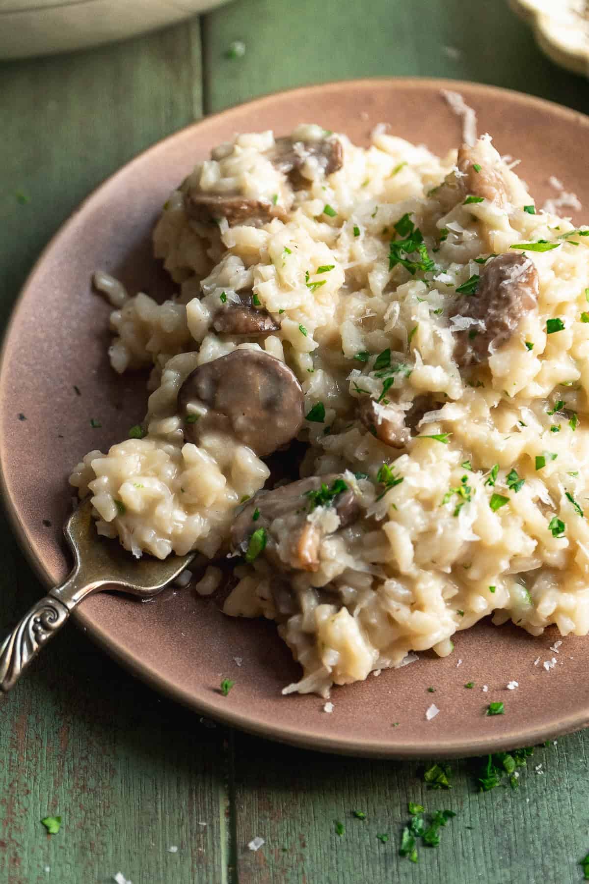 Mushroom risotto with parmesan on a plate with a fork.