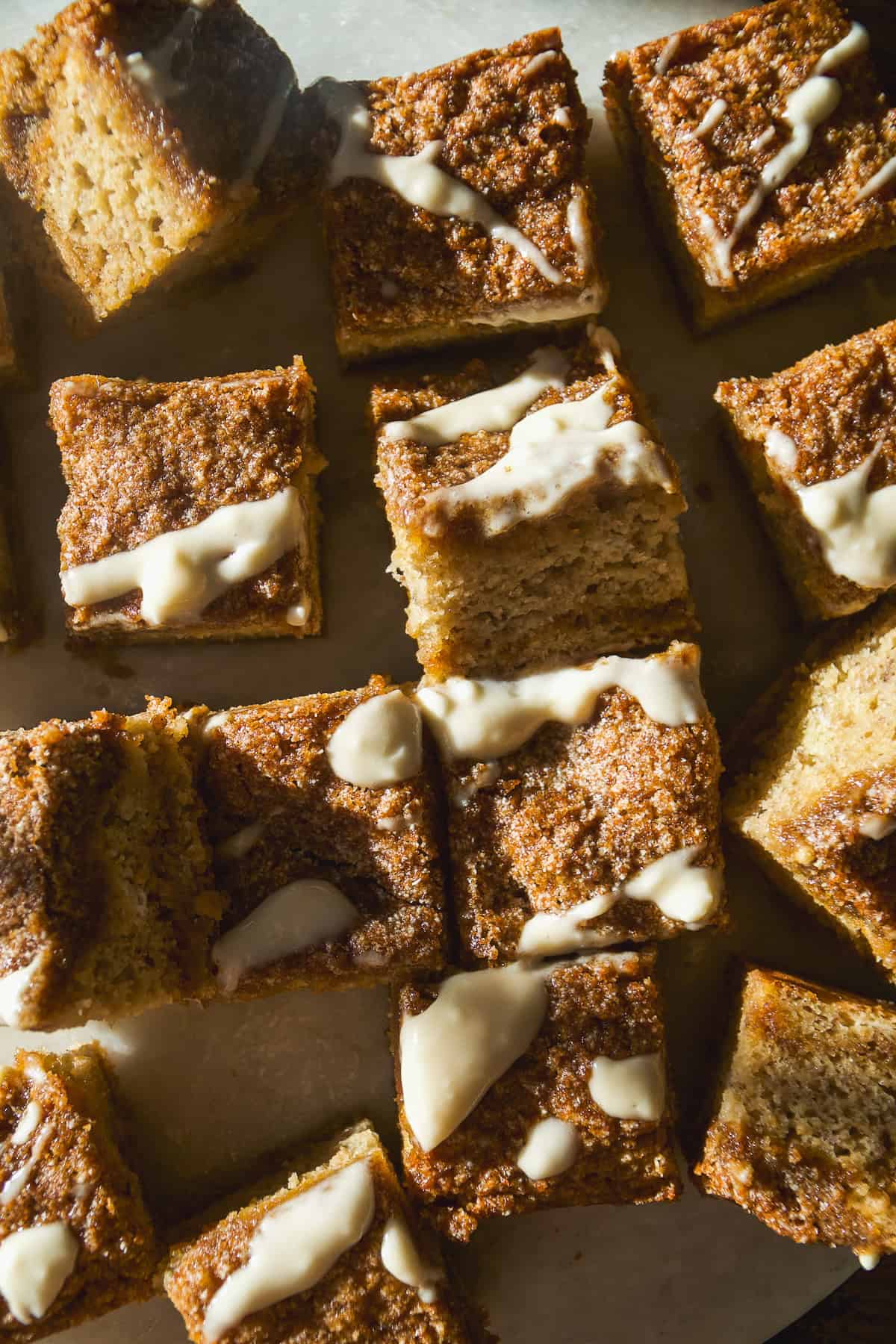 Overhead view of banana coffee cake on a platter with crumble and icing on top.