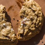 Up close view of a browned butter chocolate chip cookie cut in half on a plate.