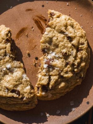 Up close view of a browned butter chocolate chip cookie cut in half on a plate.
