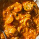 Overhead view of tomato orzo soup with chicken sausage mixed in.