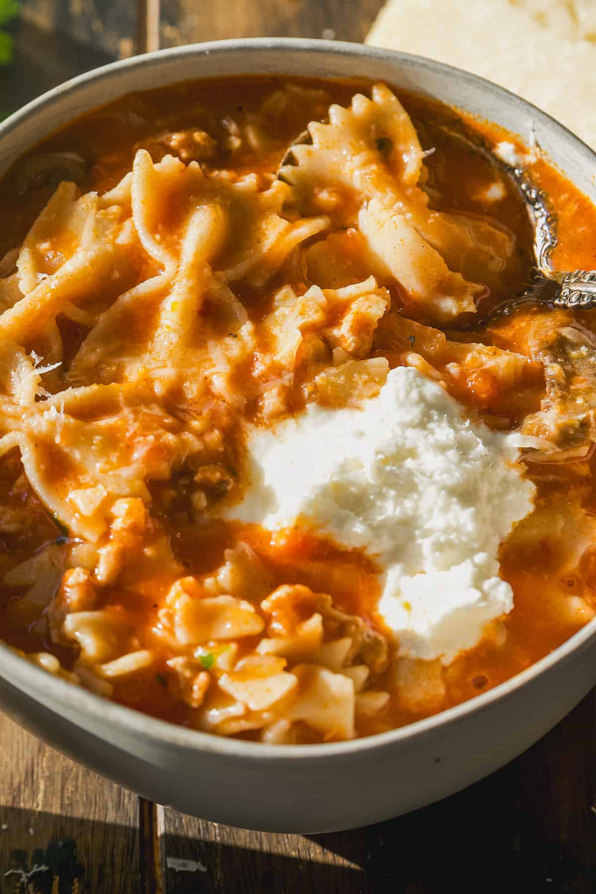 Lasagna soup in a bowl with a dollop of ricotta cheese on top.