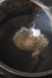Poached egg in a pot of water cooking.