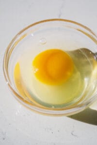 Egg cracked in a small glass bowl.