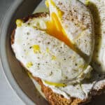 Up close view of a poached egg on toast cut in half.