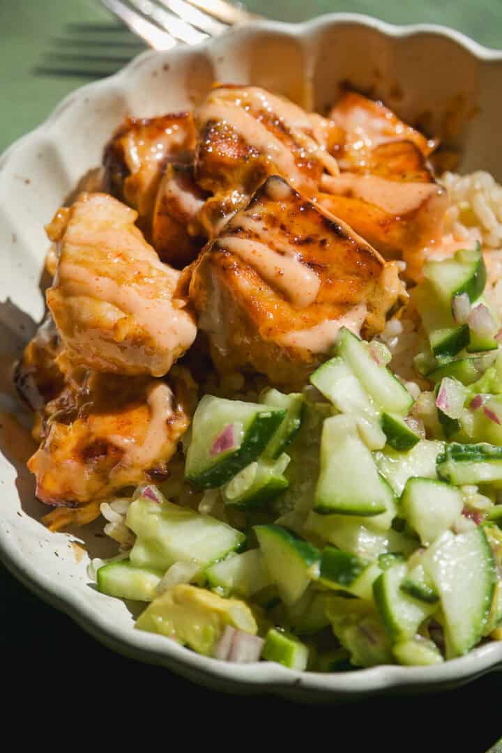 Bang bang salmon bowls with rice and cucumber salad.