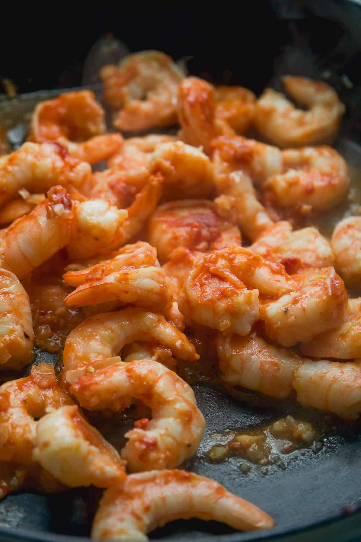 Shrimp with tomato paste cooking in a skillet.