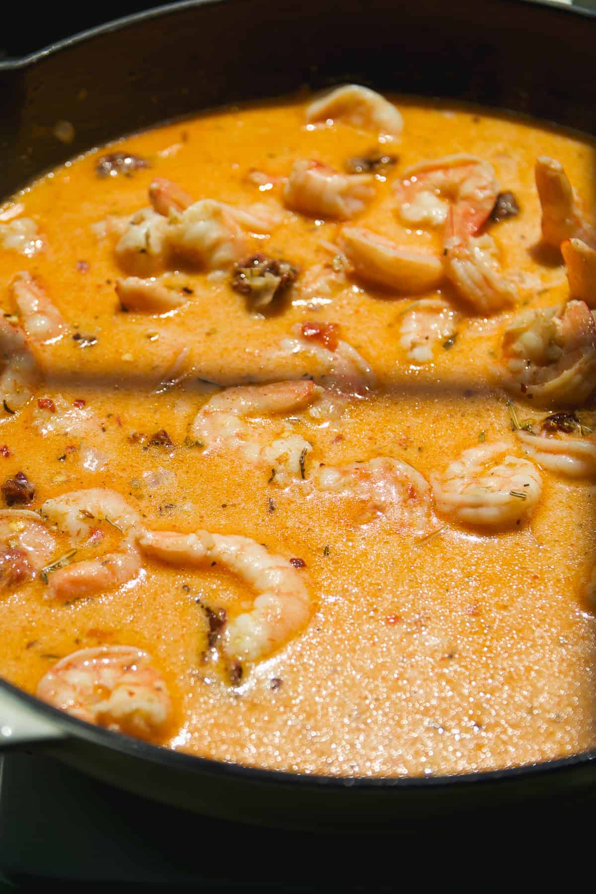 Shrimp cooking in a creamy tomato sauce.