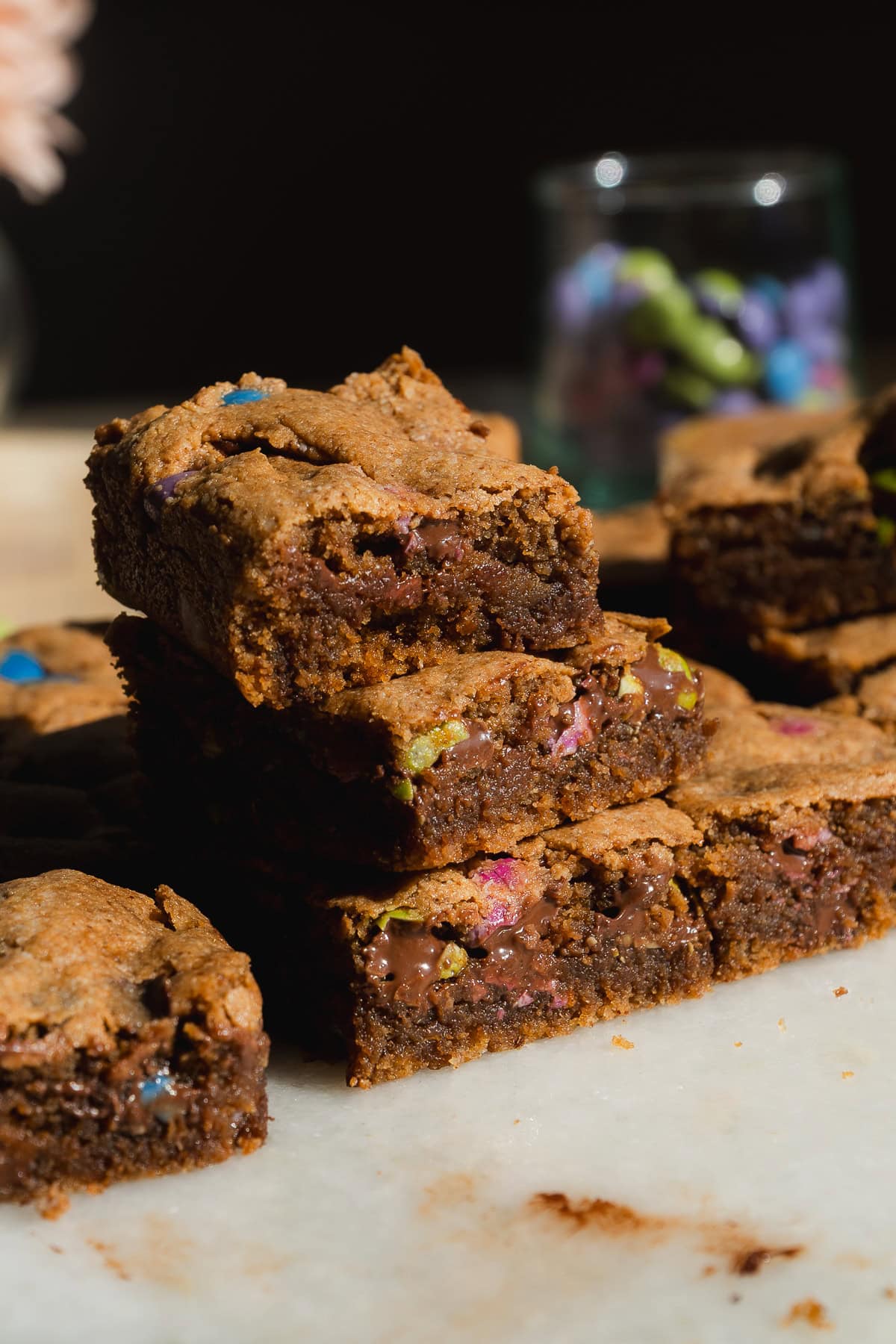 Stack of three monster cookie bars with colorful candies.