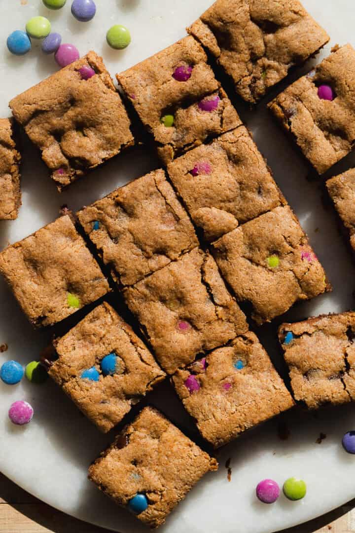 Monster cookie bars with chocolate candies on a white platter.