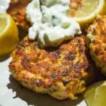 Salmon cakes on a plate with yogurt sauce on top.