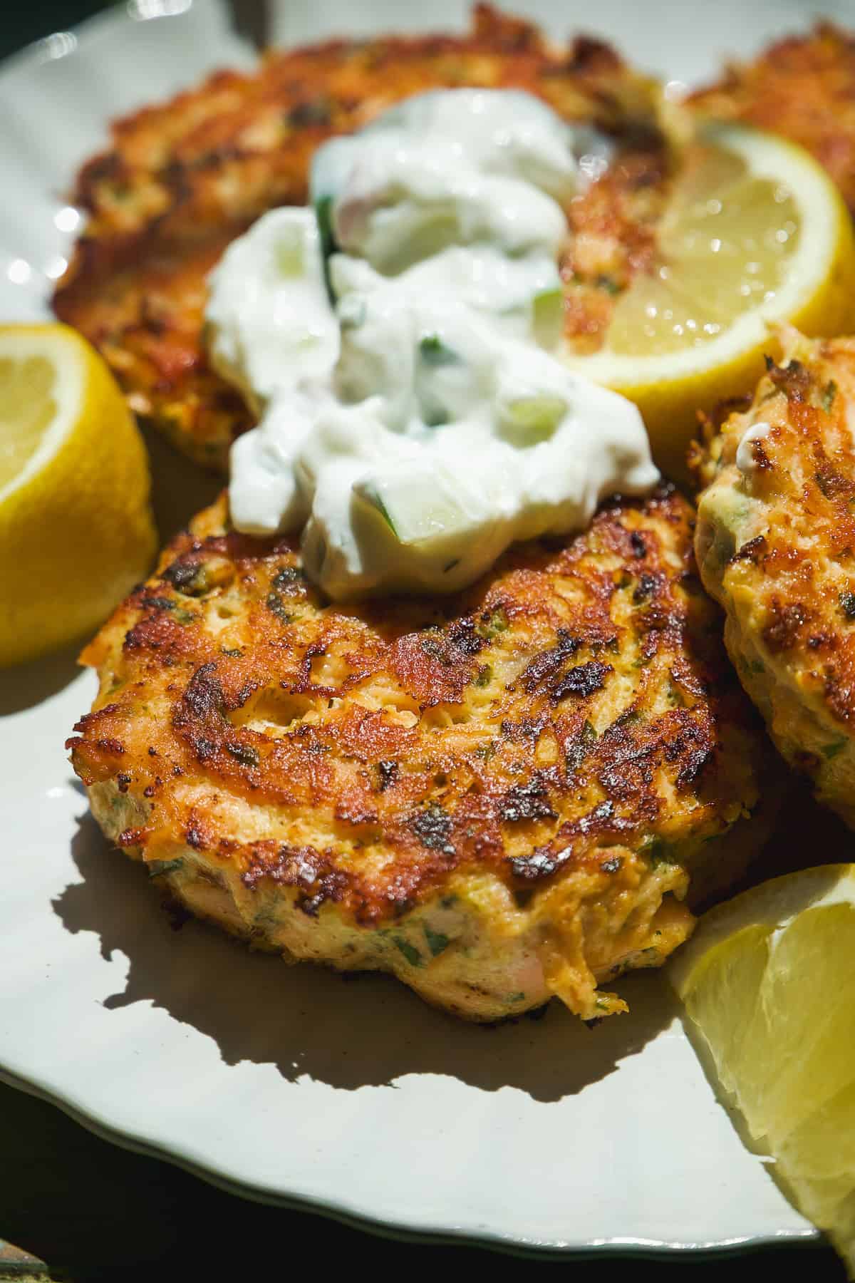 Salmon cakes on a plate with yogurt sauce on top.