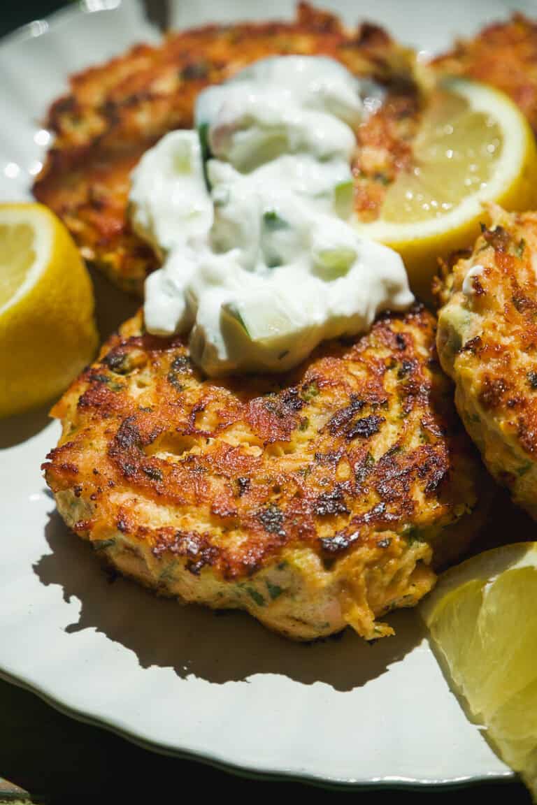 Crispy salmon cakes on a plate with yogurt dolloped on top.
