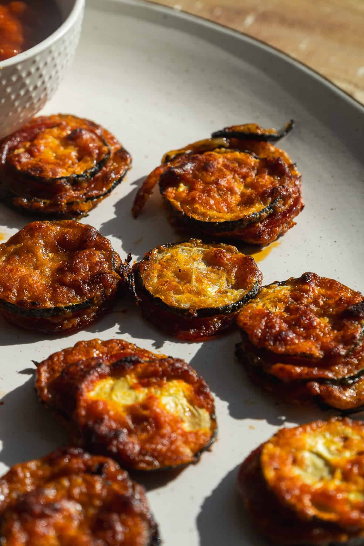 Toasted zucchini bites with parmesan cheese on a platter.