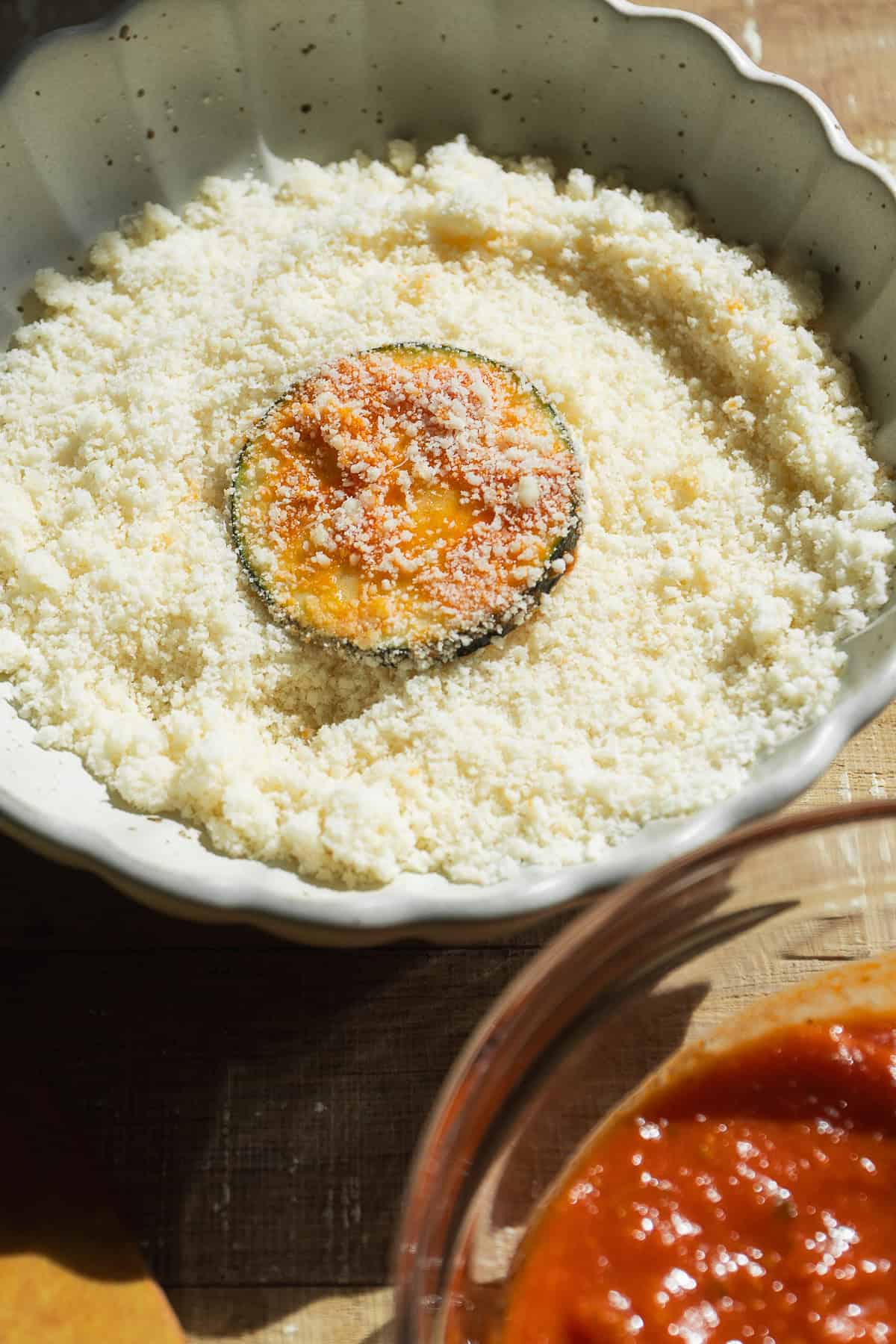 Zucchini slice coated in grated parmesan cheese.
