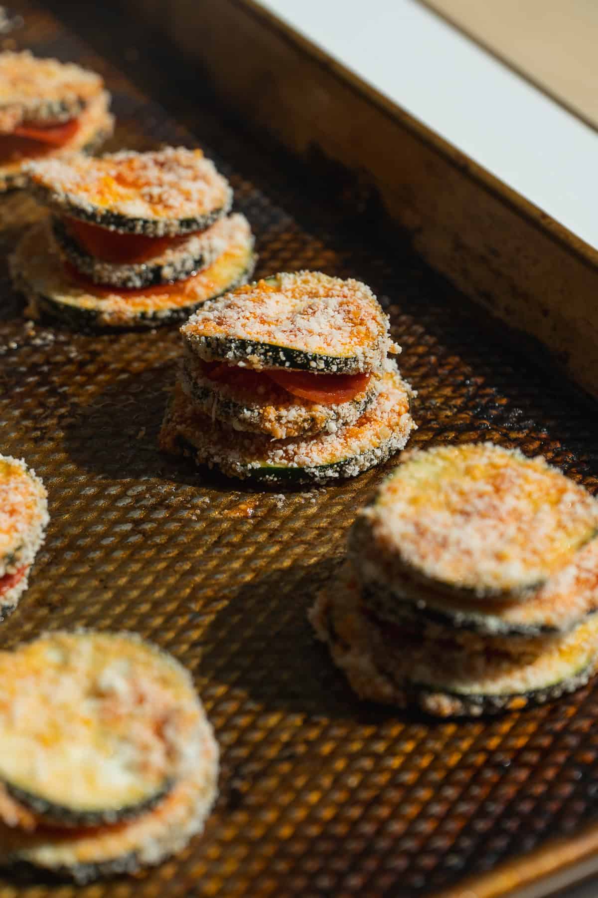 Zucchini pizza bites stacks on a baking pan about to be baked.