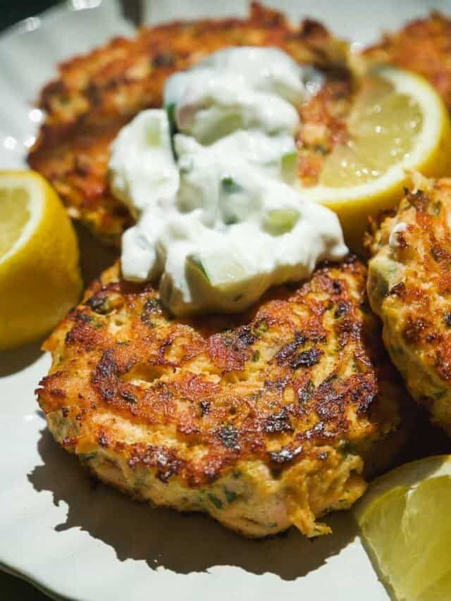 Crispy salmon cakes on a plate with yogurt dolloped on top.