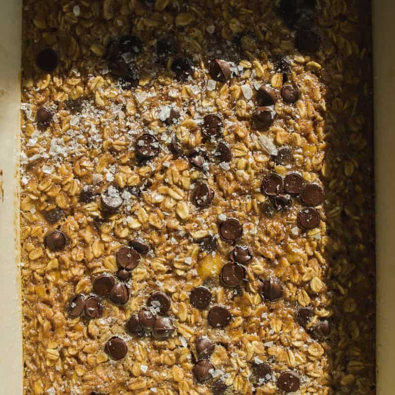 A baking dish filled with an unbaked mixture of oats, chocolate chips, and a sprinkling of salt, inspired by banana bread baked oats, ready to be baked.