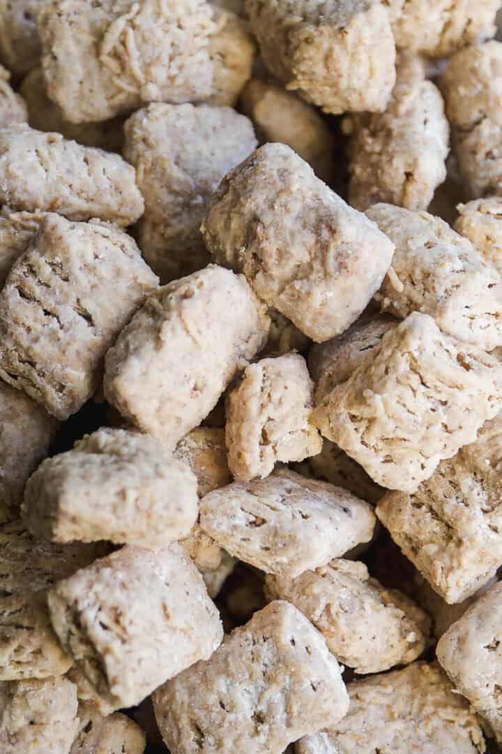 Close-up view of many bite-sized shredded wheat cereal pieces, showing their rough, woven texture and light brown color.