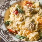 A close-up of creamy rice mixed with sliced zucchini, cherry tomatoes, and mushrooms served on a decorative plate.
