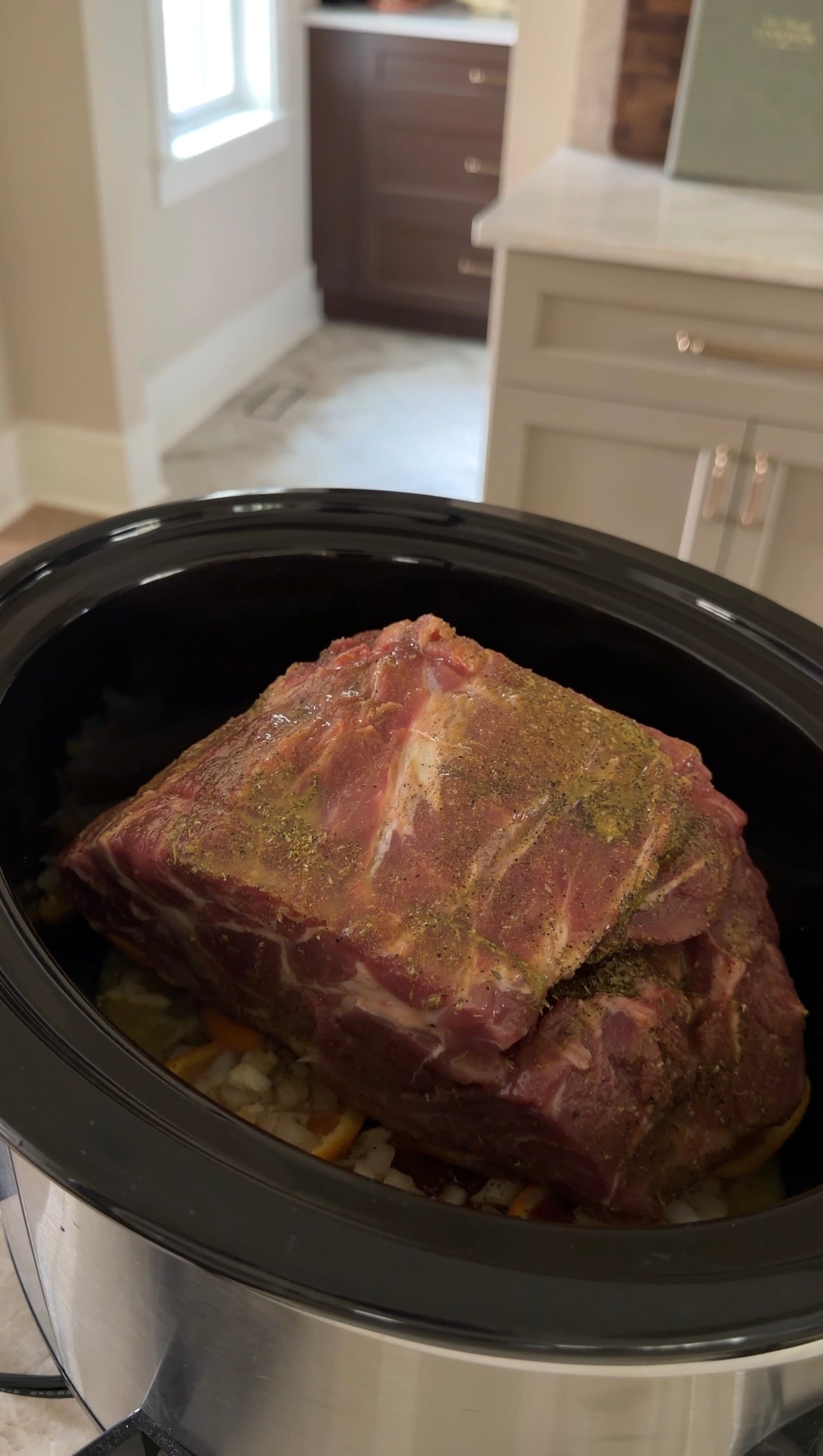 A large, seasoned raw pork roast inside a slow cooker.