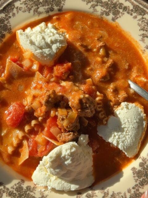 Lasagna soup in a patterned bowl topped with three dollops of ricotta cheese.