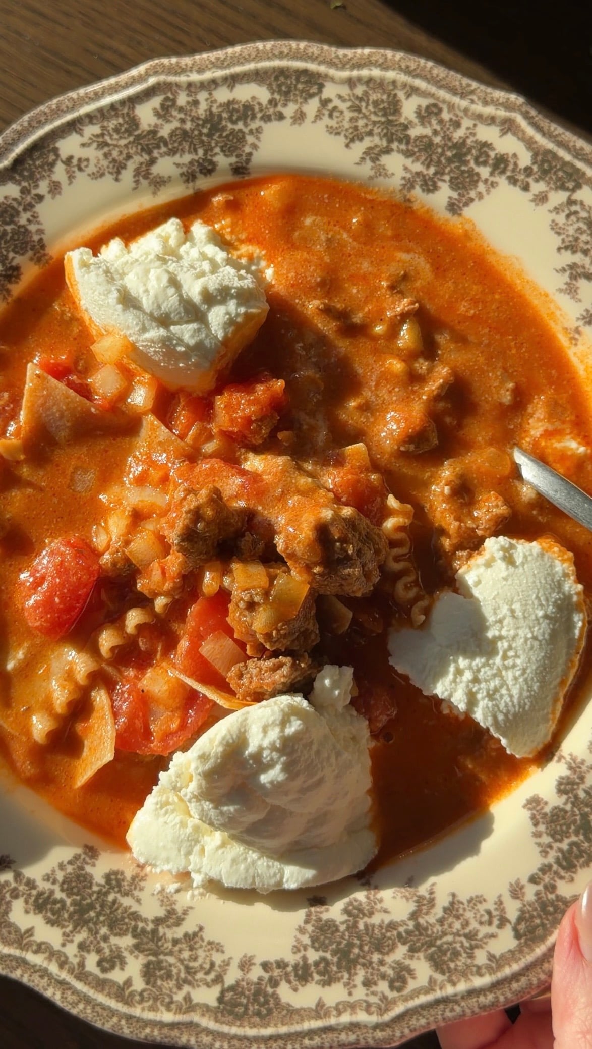 Lasagna soup in a patterned bowl topped with three dollops of ricotta cheese.