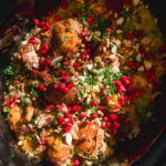 Slow cooker chicken and rice topped with pomegranate seeds, pine nuts, and fresh herbs.