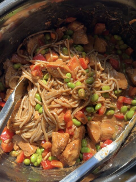 Slow cooker pasta with chicken, edamame, and red bell peppers in a creamy sauce.