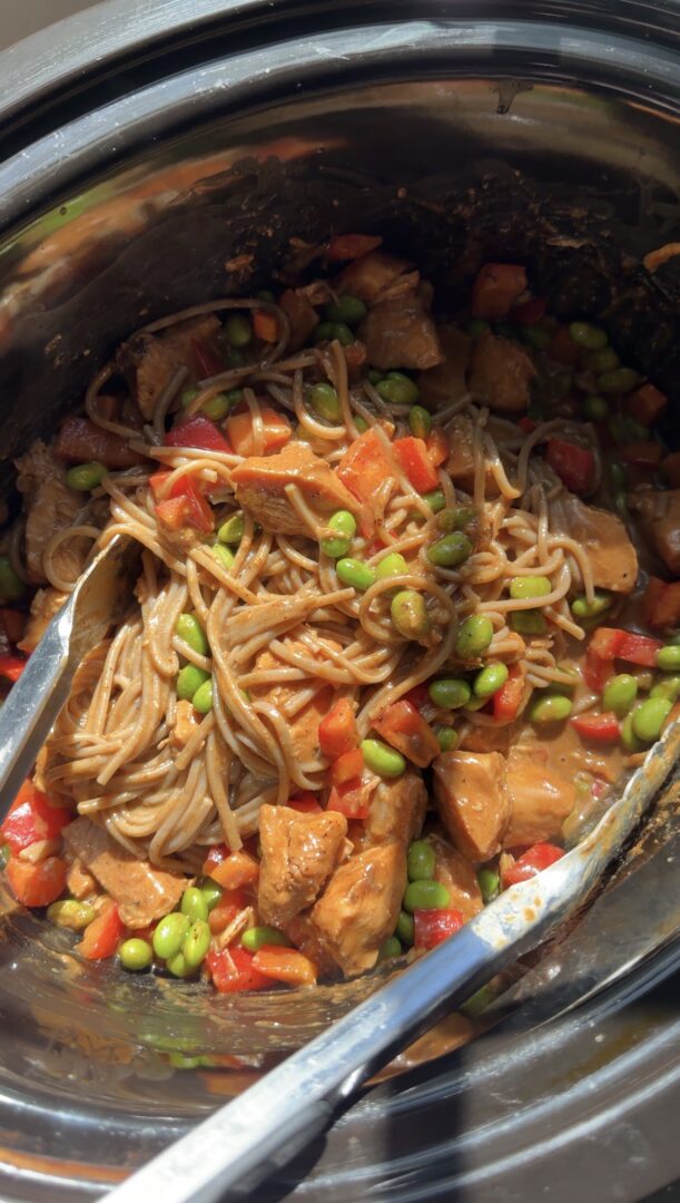 Slow cooker pasta with chicken, edamame, and red bell peppers in a creamy sauce.