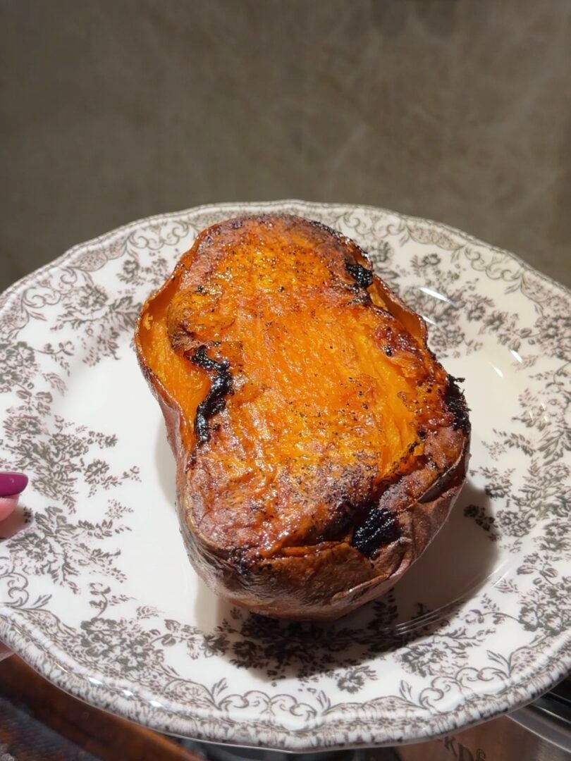 A roasted sweet potato served on a patterned white plate.