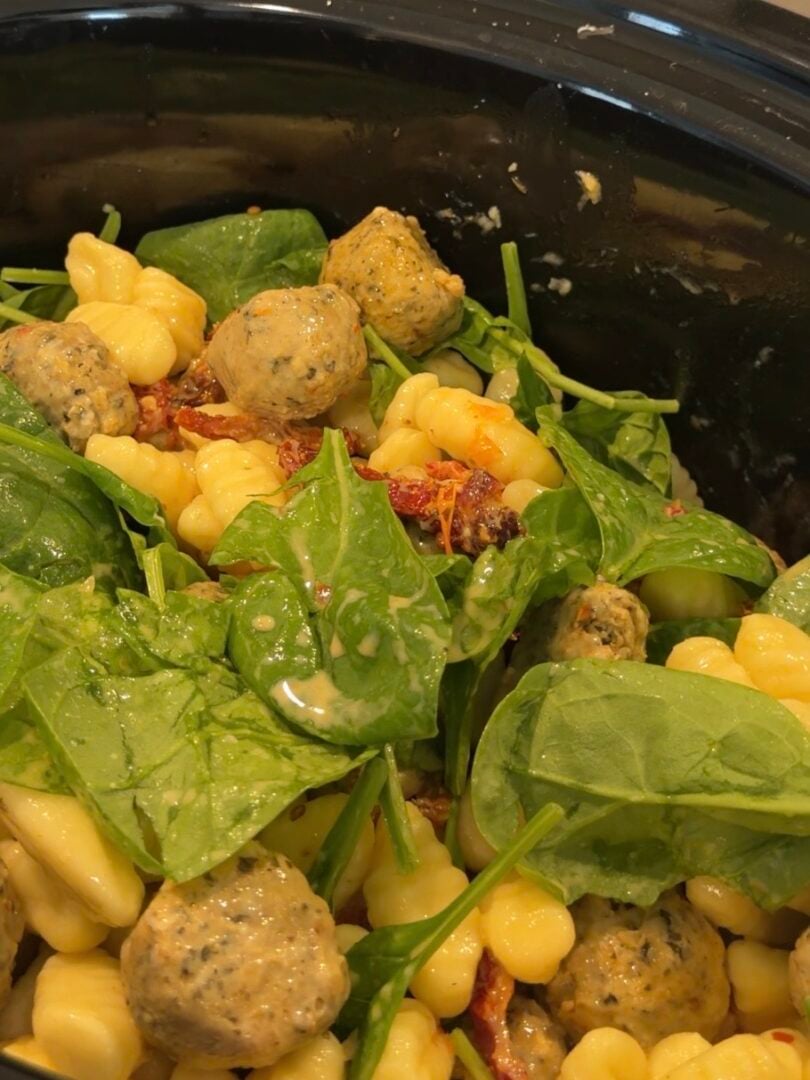 Slow cooker mixture of gnocchi, meatballs, spinach, and sun-dried tomatoes in a creamy sauce.